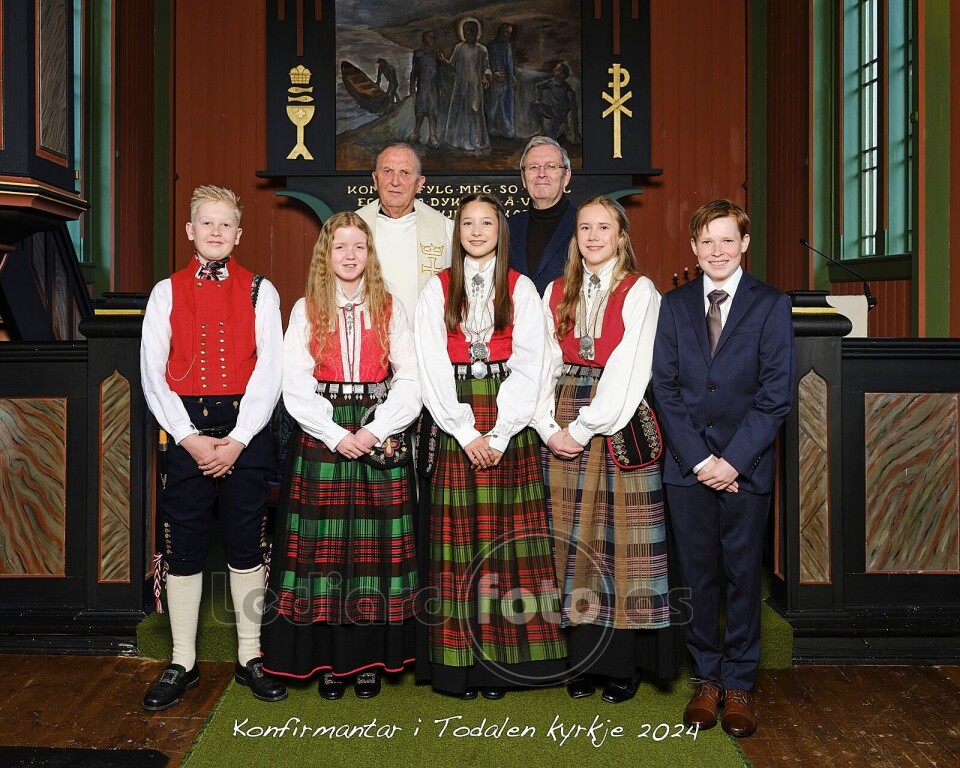 Konfirmantane med prest Torbjørn Brøske og konfirmantlærar Bernt G. Bøe. Fem konfirmanter oppstilt i koret i kirka, sammen med en prest og en mann kledd i dress.
