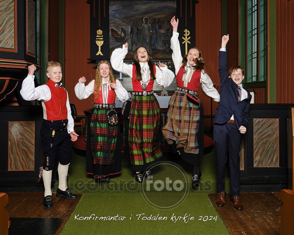 Konfirmantane i Todalen kyrkje Fem jublende konfirmanter i koret i kirka, sammen med en prest og en mann kledd i dress.