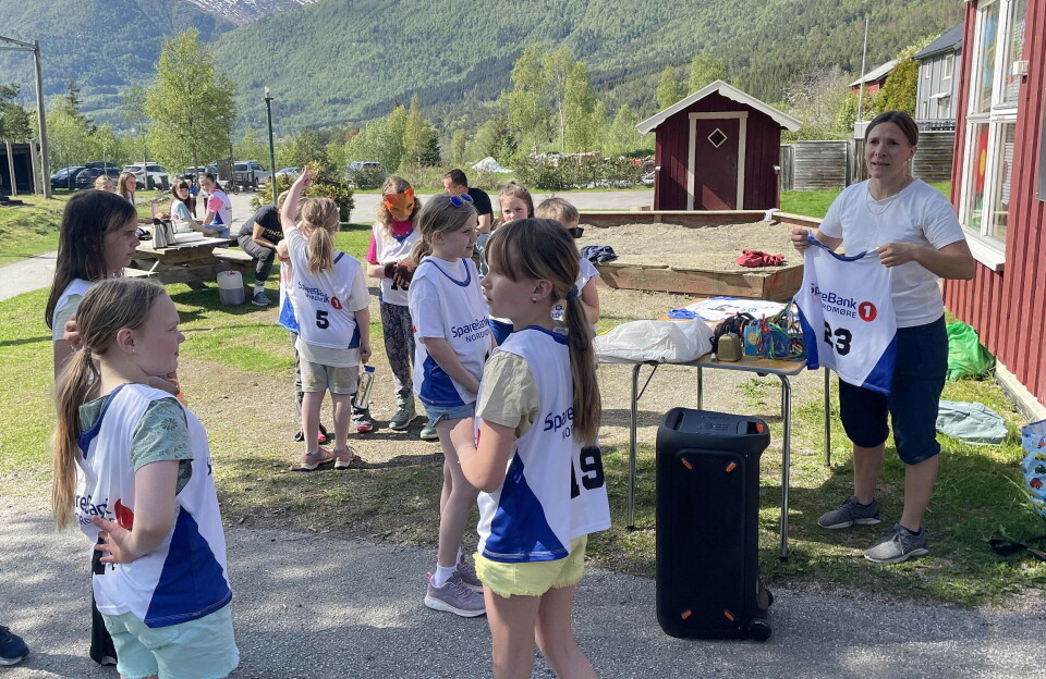 Bodil Kvam Aasbø i ei av sine mange roller – her fordeler ho drakter. Ei dame som deler ut drakter med startnummer til barn som skal løpe.