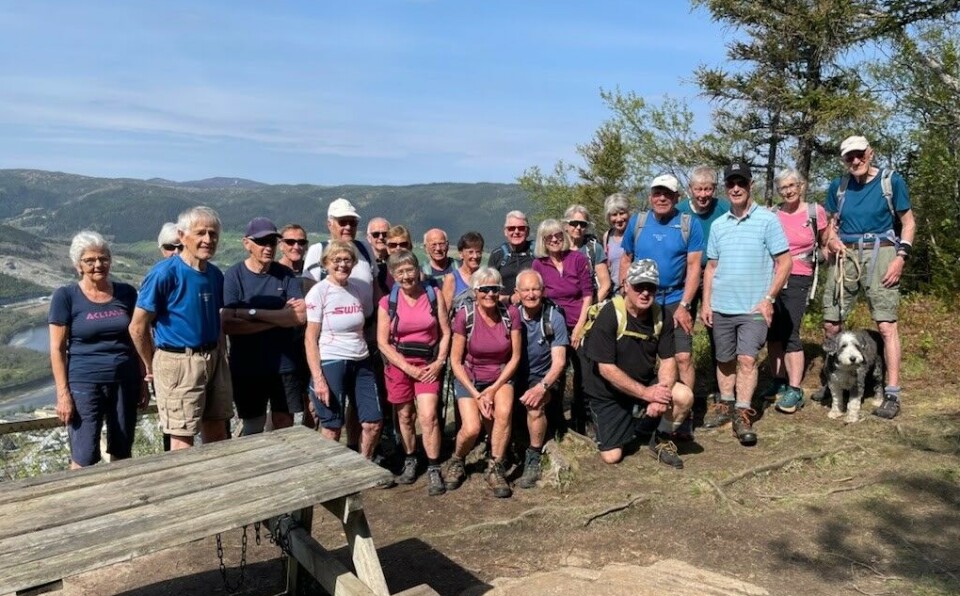 Tirsdagsturen 14. mai 2023 Ulvåsen En stor gruppe med turgåere oppstilt på en rasteplass i høyden med utsikt.