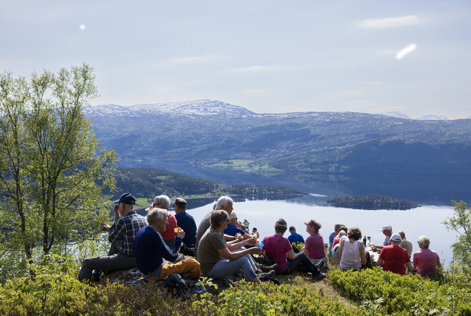Ser over Hamnesfjorden til Kjergroneset Vargøya Surnadalsfjorden og Torvik. Ei gruppe turgåere som har stoppa og tatt en hvil på en rasteplass med utsikt over fjord og fjell.
