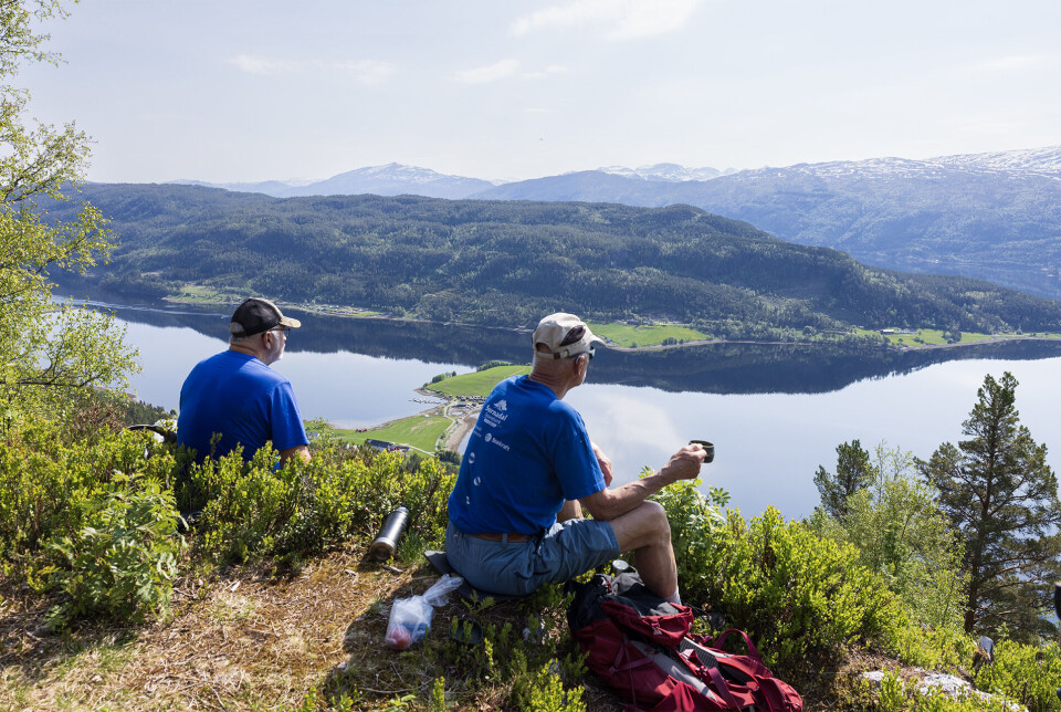 Ideell plass for kaffi og filosofering. To turgåere som har stoppa og tatt en hvil på en rasteplass med utsikt over fjord og fjell.