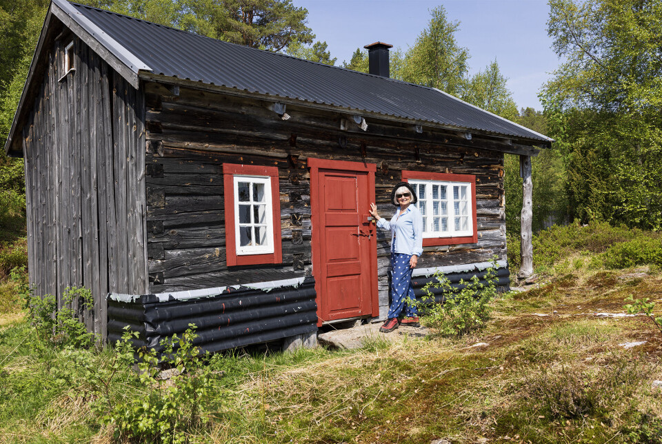 Ein skulle vore seterbudeie her, ja. Ei dame som står ved døra til et gammelt seterhus.