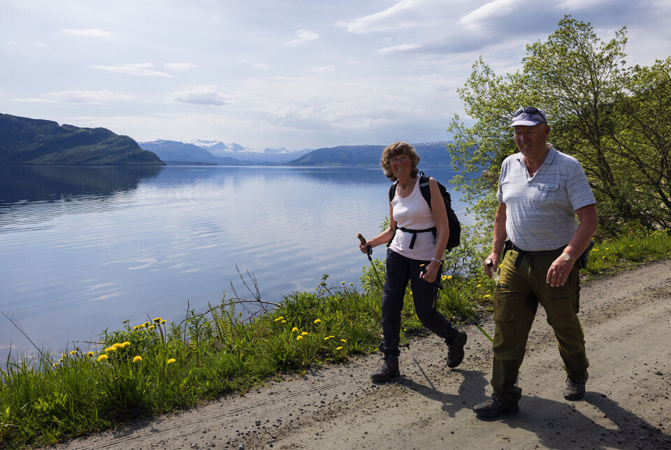 Langs stranda tilbake til Solem gard. Ei dame og en mann som går på en grusvei ved fjorden.