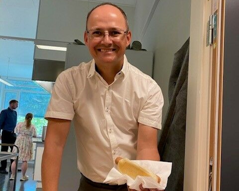 Tom Erik Kvande serverer pølse med brød. mann holder pølse med brød