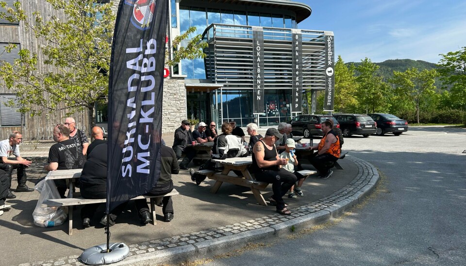 folk som sitter på benker i sola utenfor bank