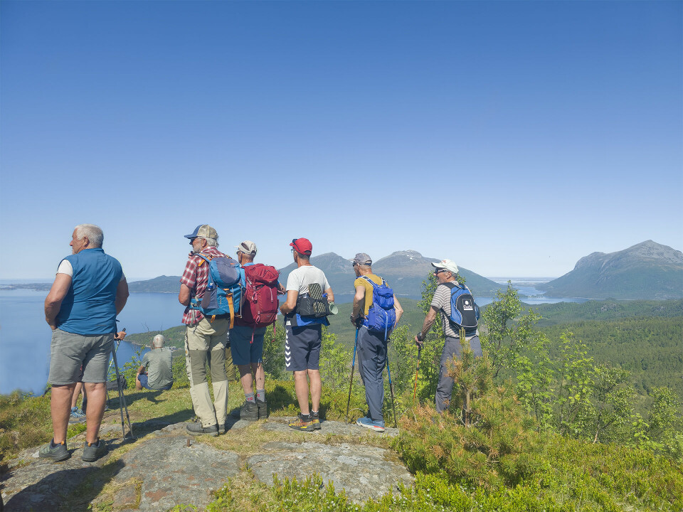 Seks turkledde menn som står på et berg og ser utover fjorden.