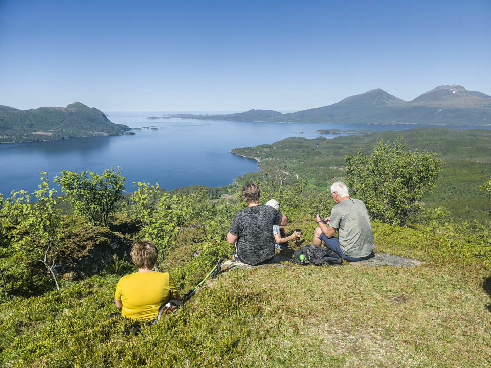 Fire turkledde damer som sitter på et berg og ser utover fjorden.