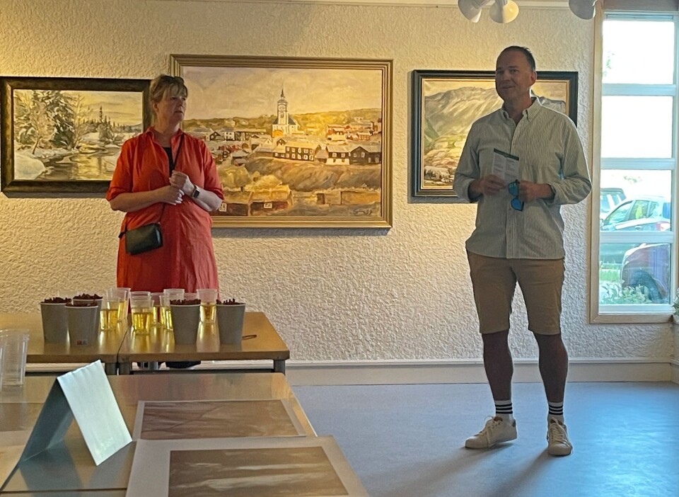 Lilli Husby og Anders Larsen åpner utstilling og vårsøghelg. Mann og dame står foran maleri av Røros by. Maleri også ved siden av, dette er vinterbilder.