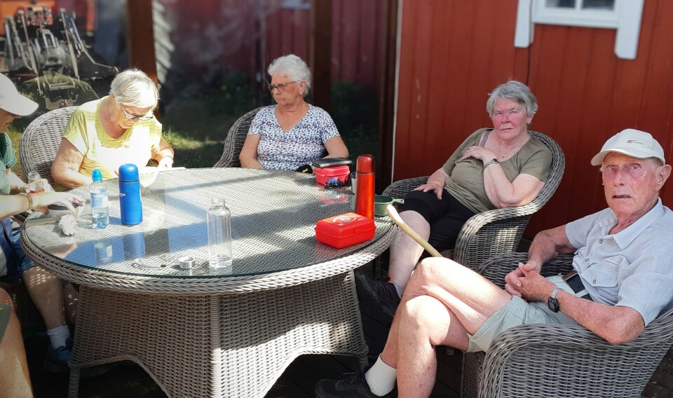 Fire pensjonister som sitter rundt et hagebord.