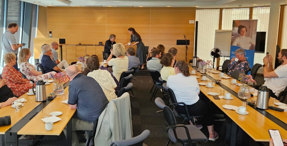 Saman for Surnadal: Innhaldsrik og interessant lunsjkonferanse. Mange mennesker i et møterom ser på to personer i enden av rommet.