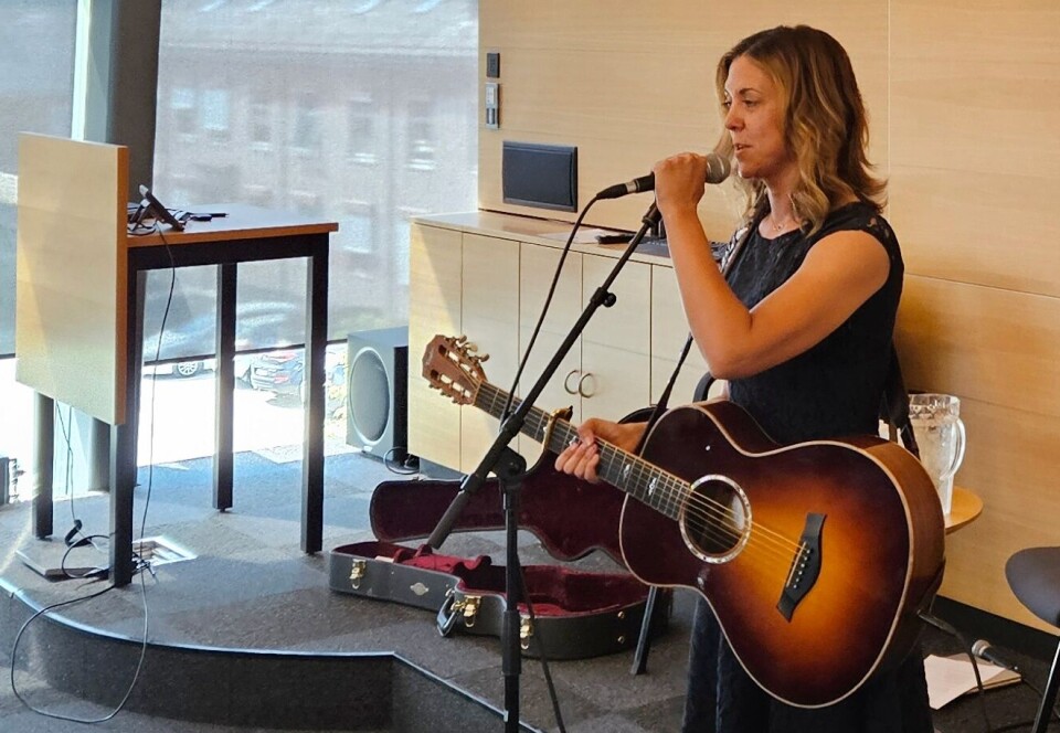 Charlotte Audestad fortalte litt om seg sjølv og songane sine. Ei dame med gitar som snakker i mikrofon.