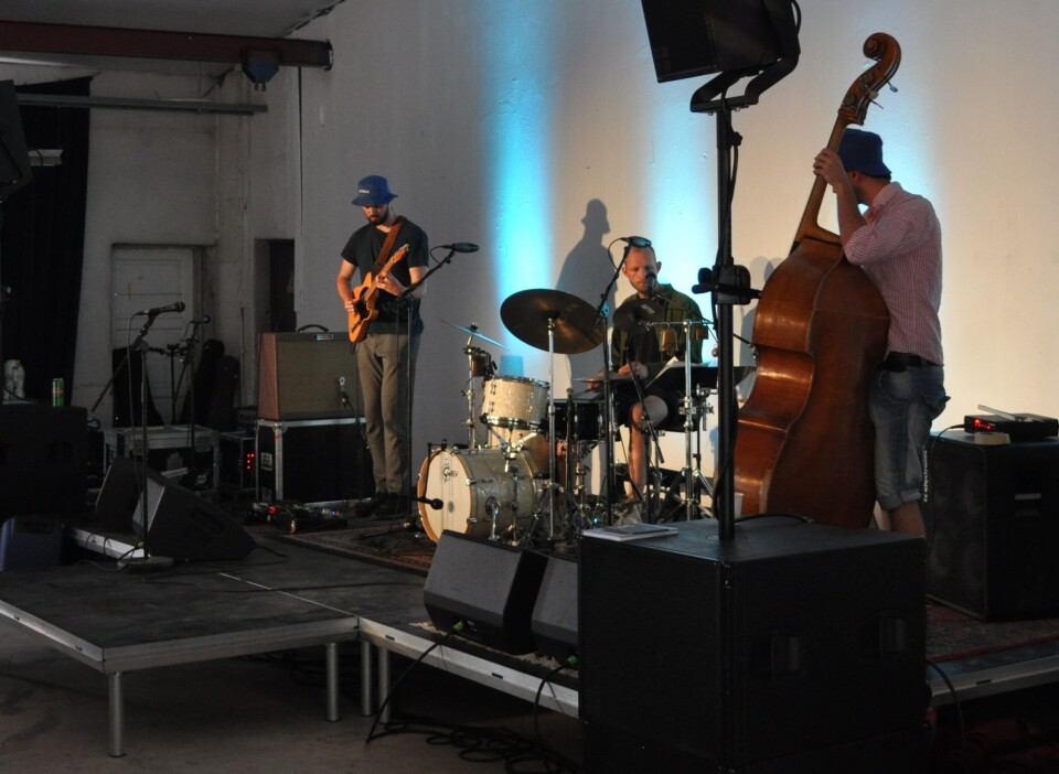 Røv Mølle Band på scenen. Tre musikere med gitar. slagverk og bass