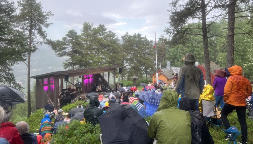 Plutseleg kom regnet. Heldigvis gjekk det fort over, og publikum kunne igjen tørke seg i sola siste del av Kleivakvelden. folk med paraply foran Kleivascenen