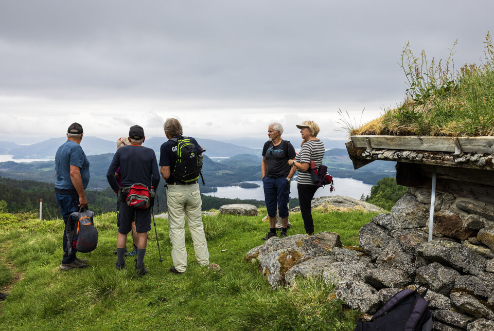 Vakkert og vidt utsyn fra Nysetra. turgåere ved ei gammel steinhytte. Fjord og fjell i bakgrunnen.