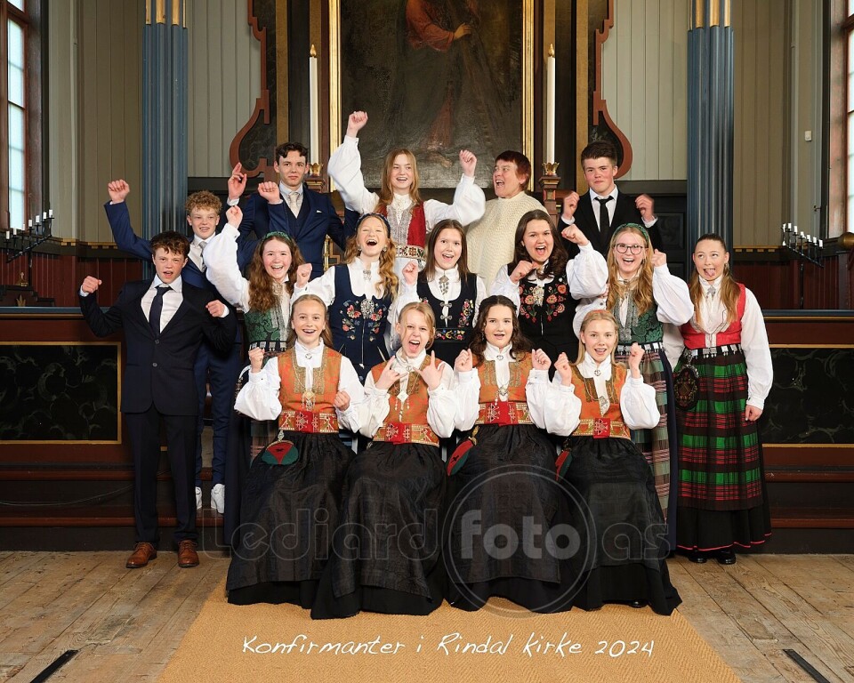Konfirmantene i Rindal kirke 16 jublende konfirmanter og en prest i koret i kirka.