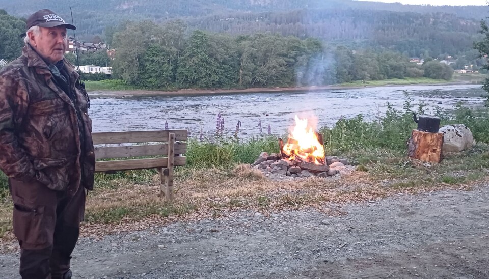 Øyvind Holte sørger for at fiskerne får god forpleining. mann foran bål ved elv