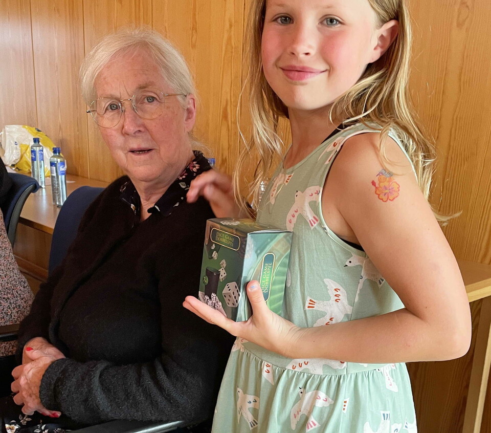 Katrine og bestemor vann konfekt på utlodninga. Ei eldre dame og ei ung jente med ei eske i handa.