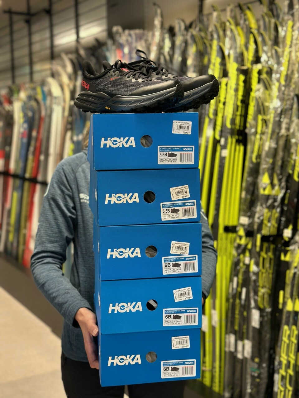 Ei dame med en stabel med Hoka-skoesker.