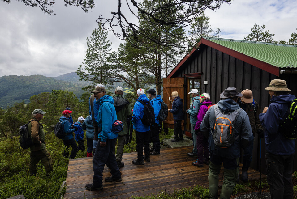 Anne-Sissel viser stor gjestfrihet på Nebbu. Mange turkledde folk ved ei hytte i marka.
