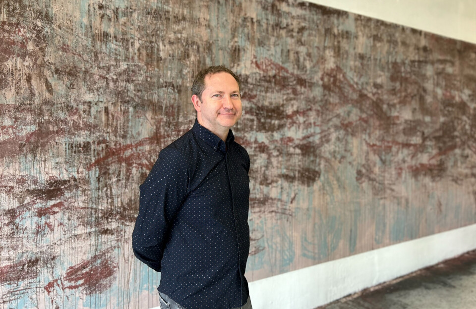 Māris Čačka er kunstner og direktør ved Mark Rothko Art Center. En mann som står foran et stort maleri i duse toner, malt rett på en vegg.
