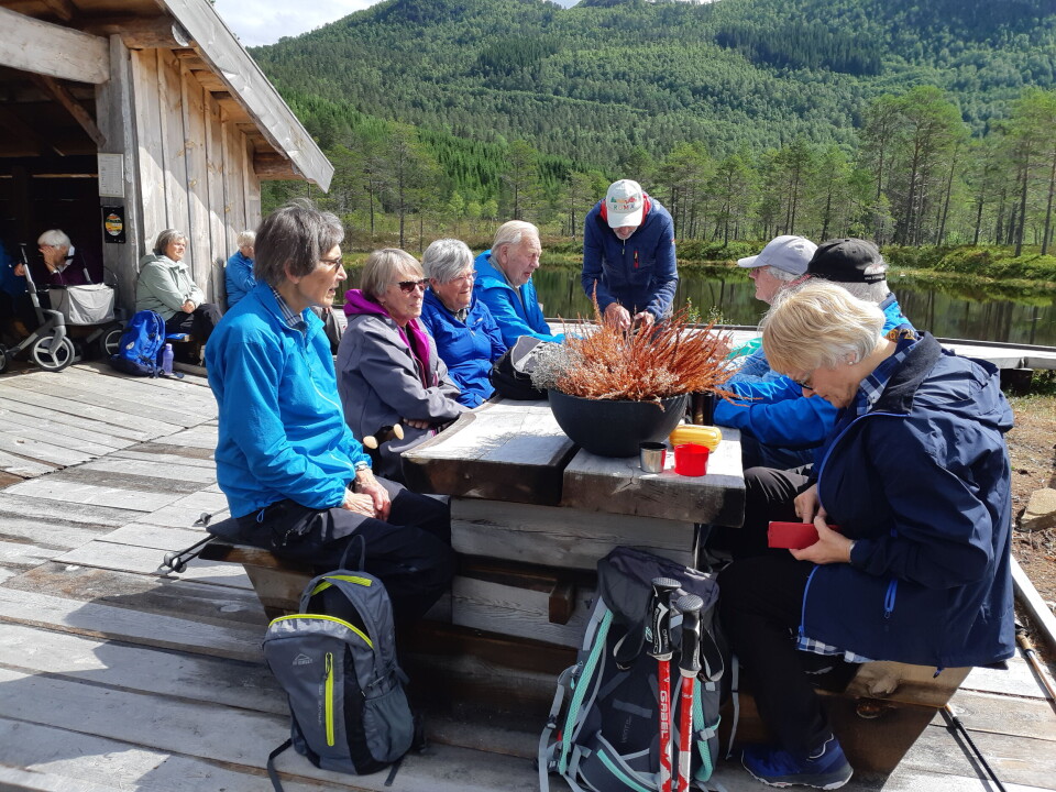 Mennesker spiser mat rundt et bord ute på tur