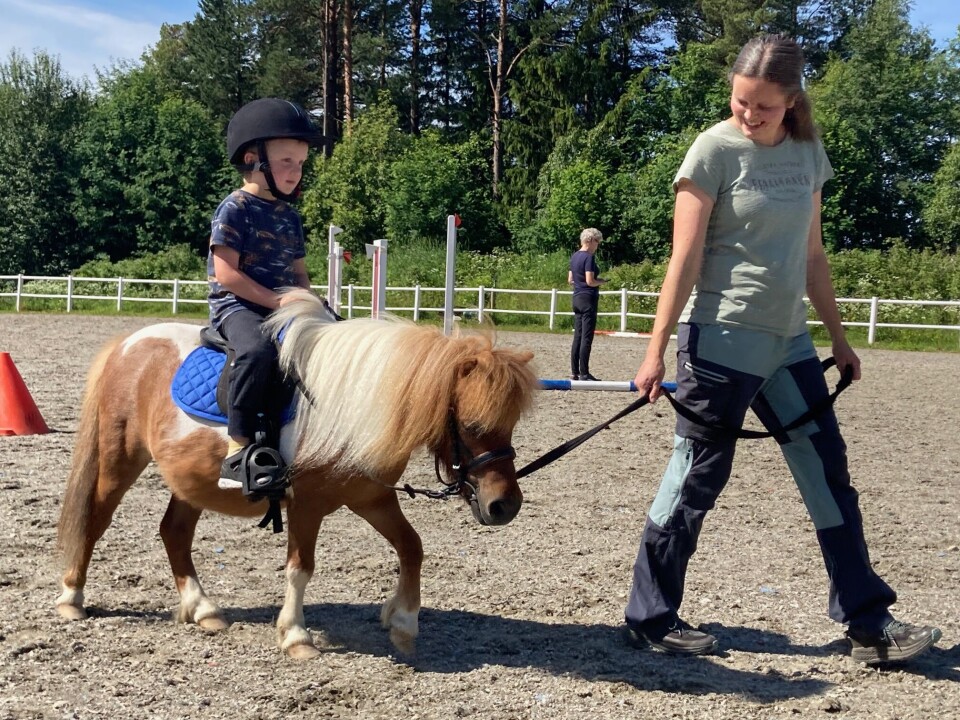 Mathias på 4 år var stevnets yngste rytter, men han var dypt konsentrert hele runden og var meget stolt etterpå. Liten flekkete ponni med en ung gutt på ryggen mens mor leier.
