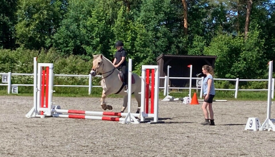 Fjordingen Embla i fint driv med sin unge rytter i 20 cm -klassen mens trener Silje Mari Husby følger med Jente som hopper med en fjordhest