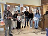 5 jenter og to menn foran et piano