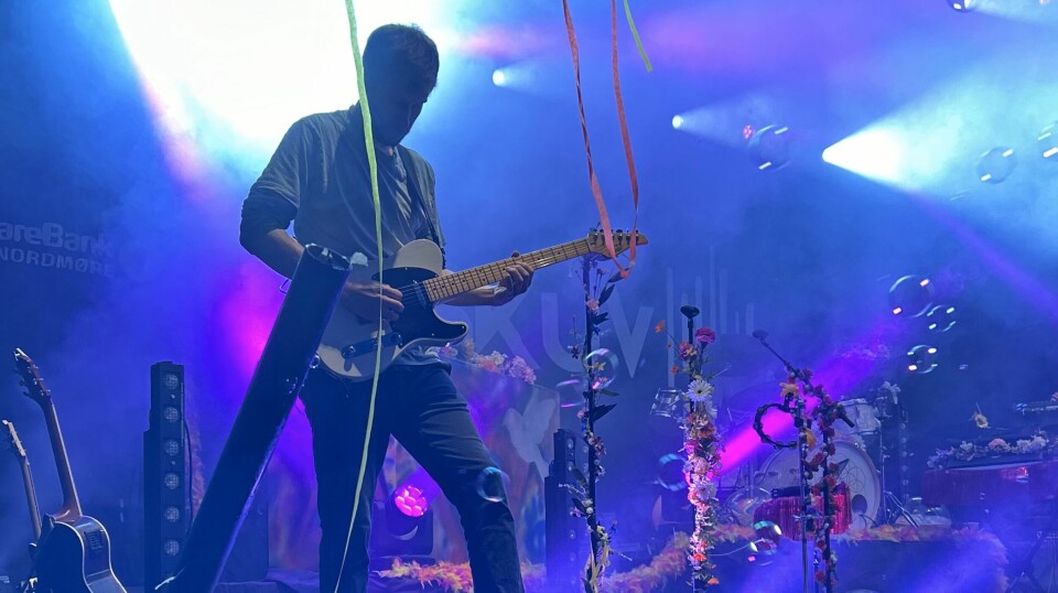 En gitarist som står på scenen og spiller.