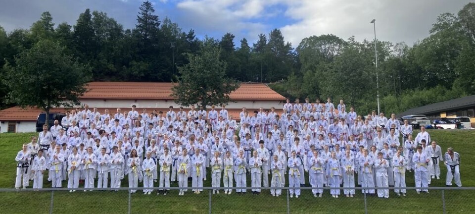 Mange taekwondo-kledde ungdommer oppstilt ved friidrettsbanen på Øye