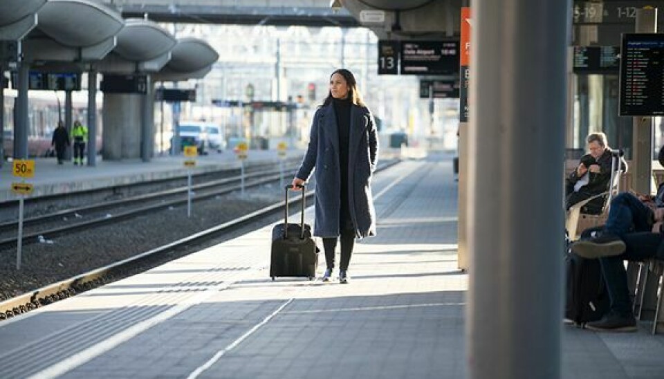 En kvinne går med en koffert på en togstasjon