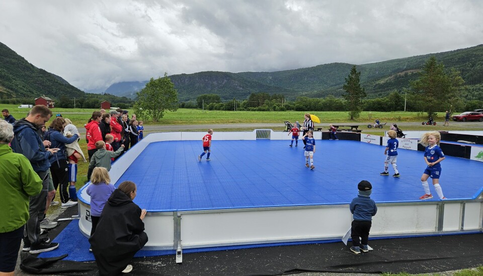 Barn spiller fotball i en blå fotballbinge
