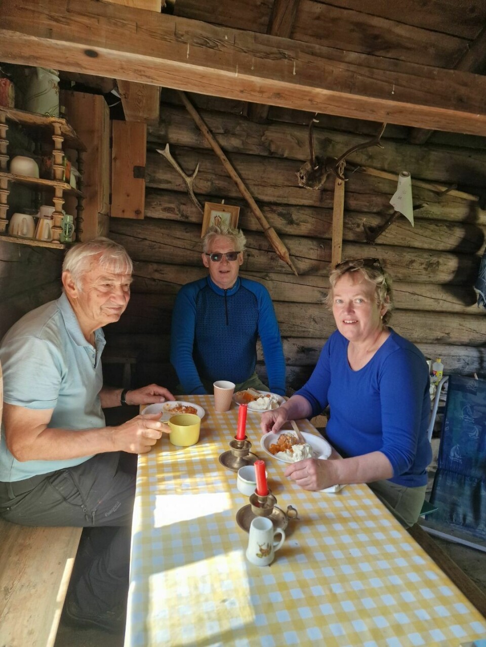 tre folk ved bord i hytte