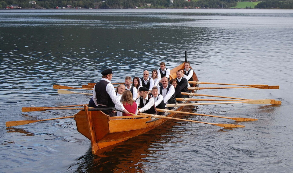 På kyrkjebåten «Hjelmkonnå» kan ein delta i «bua-roing». Dette set preg på arrangementet (Arkivfoto) Menn i robåt