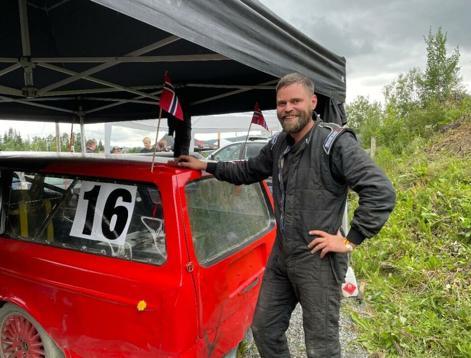 Frank Røen med Volvoen sin pyntet med flagg og blomster. Dette bildet ble tatt i pausen av billøpet i helga. Mann ved en bilcrossbil med to norske flagg på toppen av bilen og en blomst på siden av bilen.