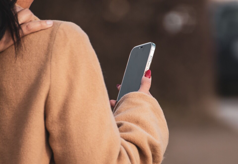 Unngå denne ferie-svindelen Ei dame som holder en mobiltelefon i handa.