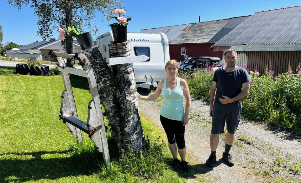 Unni og Erling med skilt til gjenbrukslåven hjemme på gården. Ei dame og en mann som står på et gårdstun.