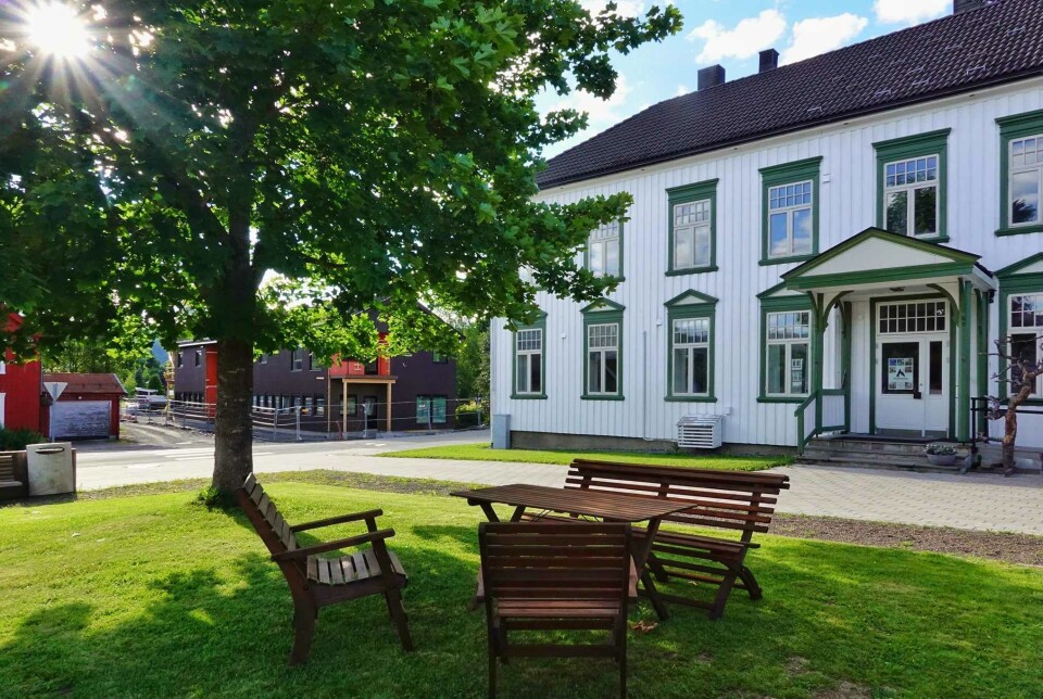 Lek i parken med mange aktiviteter - uformelt gratis tilbud En enldre trebygning med plen foran, bord og benker.