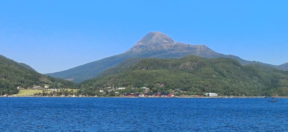 Innover Bøfjorden fra Bøsaga mot Settemsøran og med Hjelmen i bakgrunnen. Fjord og et høyt fjell.