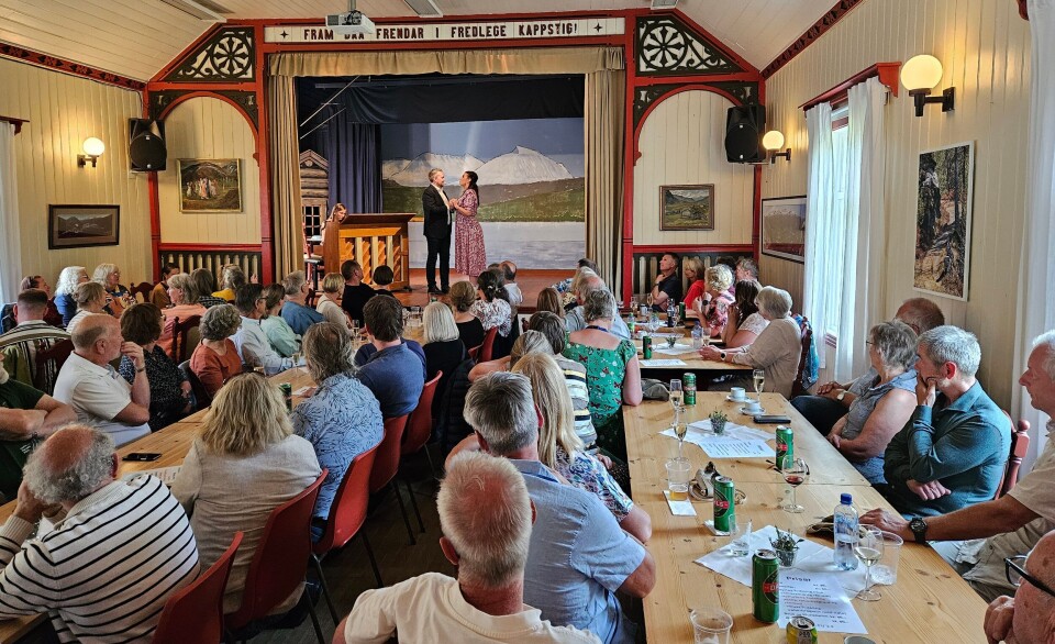 Bra med folk på operakveld i Todalen ungdomshus. En fullsatt sal i et forsamlingslokale, med ei dame og en mann på scenen.