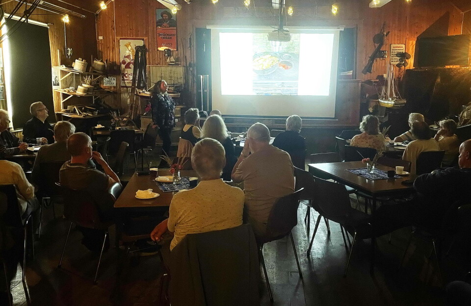 Stor interesse i salen under biletkåseriet. Et forsamlingslokale full av folk som ser på bilder på et lerret.