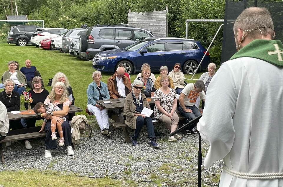Vidar Rygh leier gudsteneste på den fine arenaen. En prest som preker i mikrofon for en forsamling utendørs.