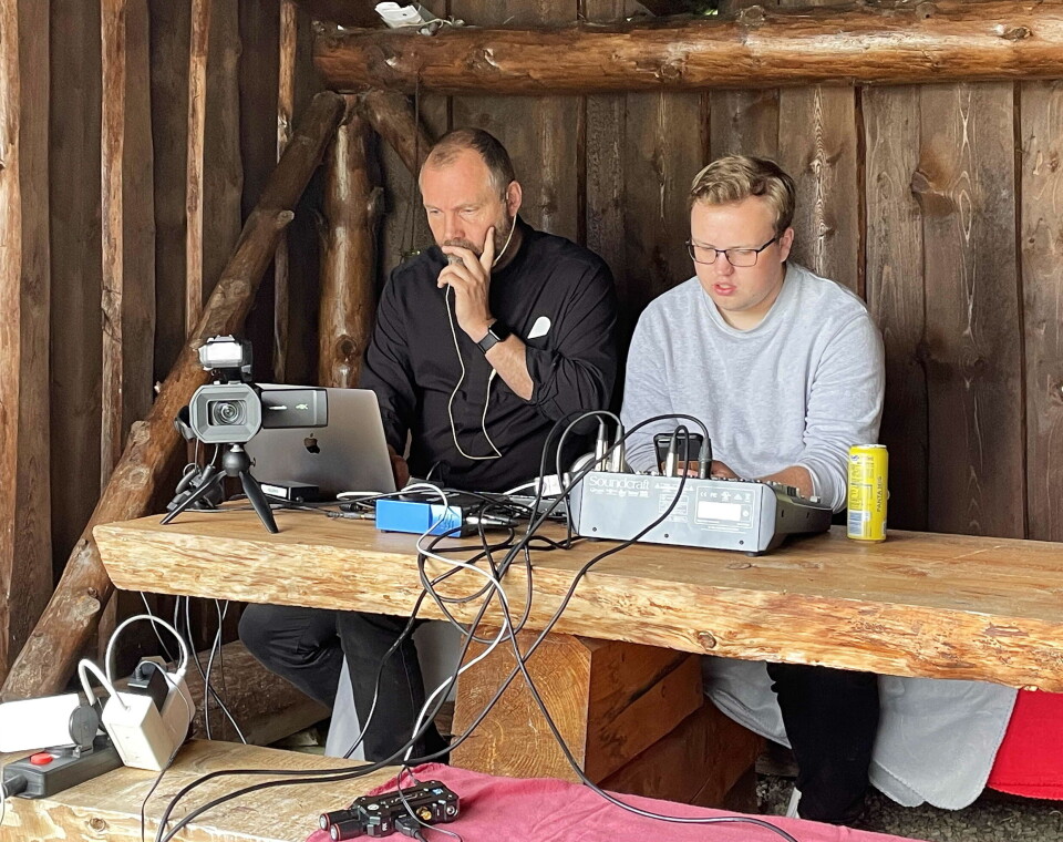 Frå gapahuken styrte Olav Lindvåg (t.h.) fjernsynsopptak til streaming, med prost Vidar som regissør. To menn som sitter inne i en gapahuk med noen elektroniske instrumenter.