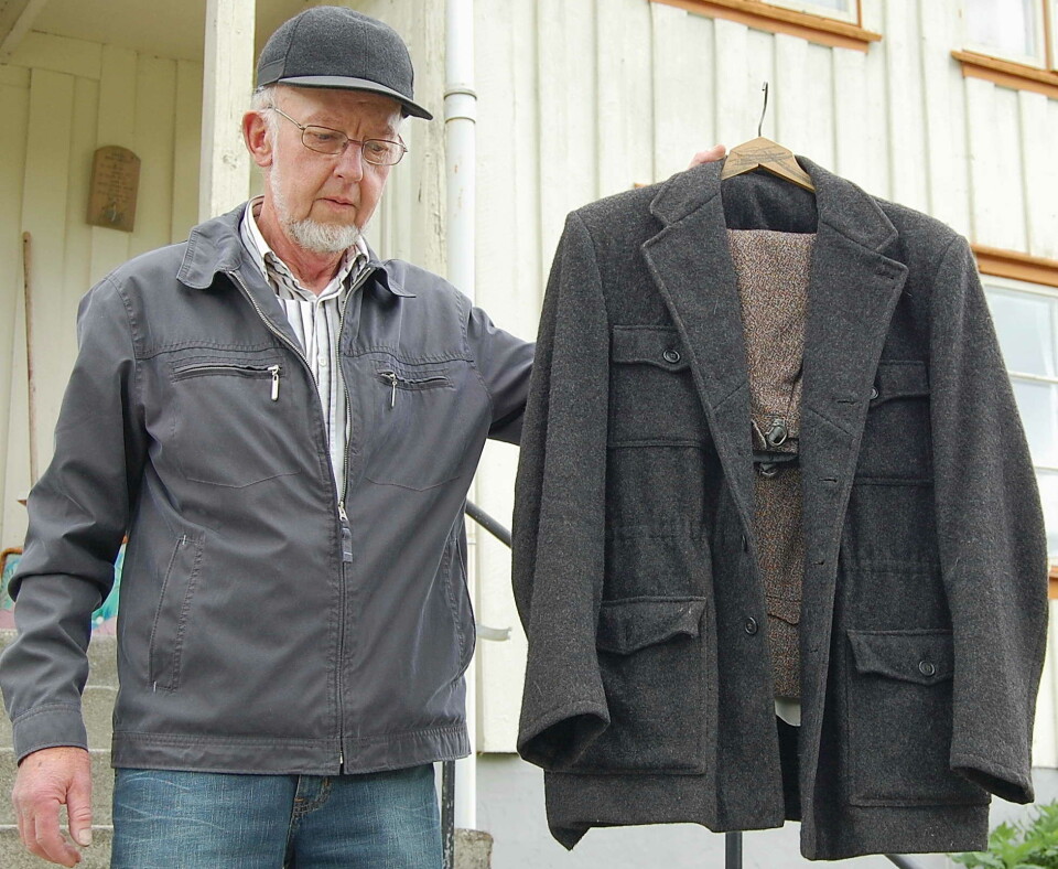 Helge Settemsdal viser ein Hjelmen-dress. En mann som står og holder opp en gammel jakke.
