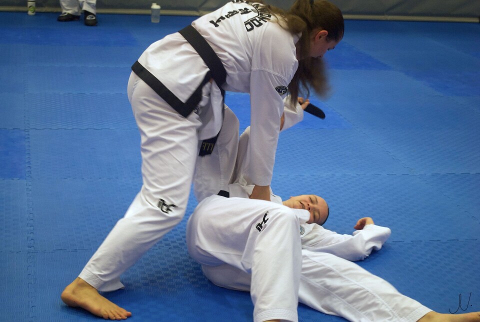 Her trener to utøvere fra Trondheim Taekwon-Do Klubb selvforsvar. To taekwondo utøvere utfører selvforsvar hvor den ene står mens den andre ligger på bakken.