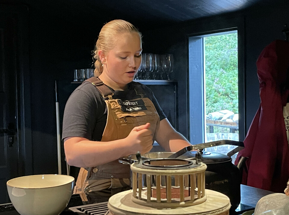 Anna Tomine Elshaug- Heggset koker grøt til bakelsene. Hun trives med sommerjobben på Trollheimstunet En ung dame står foran en kjøkkenbenk og rører i en kasserolle