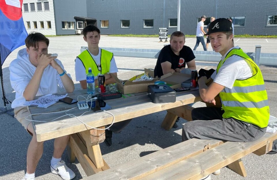 Orion Fossen og August Sjøflot i gule vester ordnet med billetteringen. Her sammen med Lars Ole Betten og Odin Hoem under en paviljong i sommervarmen. Fire ungdomsgutter