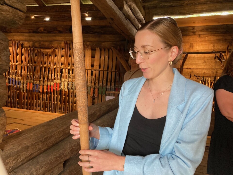 Sigrid Fivelstad viser frem en skistav med utskjæringer fra hjemgården, datert til 1882. Dame med blå dress som viser frem en skistav i tre med treskjæringer i.