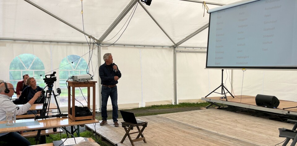 Inge Helgeton viste en oversikt over mange etternavn fra Rindal, som er representert på Løkken og Bjørnli. En mann med mikrofon foran et lerret.
